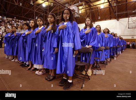 Multiethnic middle school girls wearing blue graduation gowns recite ...