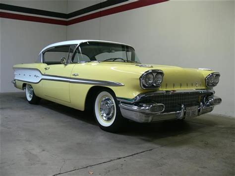 an old yellow car is parked in a garage with whitewalling and chrome trim