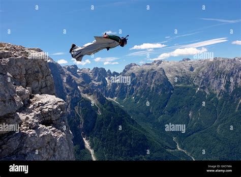 Wingsuit BASE jumper is flying from a cliff Italian Alps, Alleghe ...