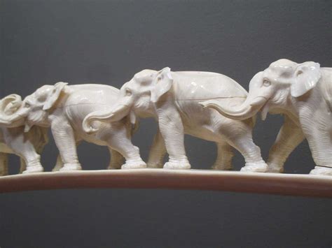 An ivory elephant tusk carved with twelve graduated elephants on a carved naturalistic stand ...