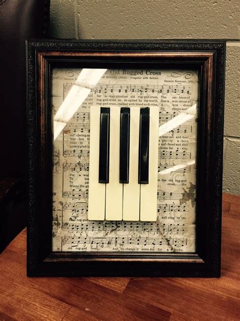 an old sheet music with piano keys is framed in a black frame on a wooden table