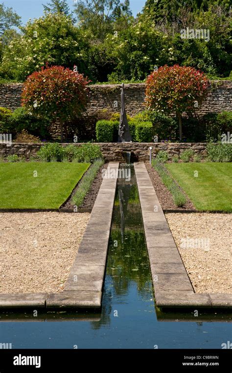 Rill water feature edged with lavender in walled private garden laid out in a formal style with ...