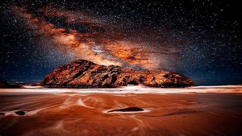 the night sky is filled with stars above a rocky outcropping in the desert