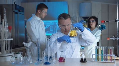 two men and a woman in lab coats are doing experiments