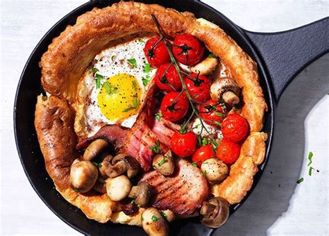 a skillet with bacon, mushrooms, tomatoes and an egg on top is shown