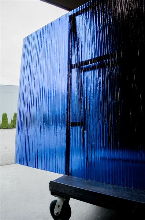 a blue building with a black bench in the foreground and trees in the ...