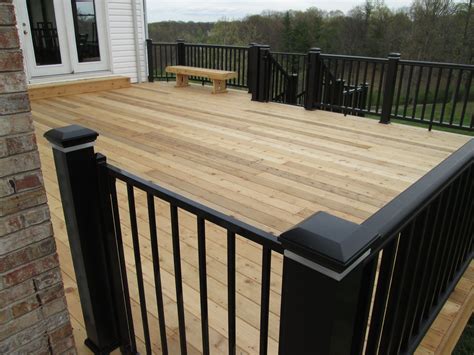 a wooden deck with black railings and a bench