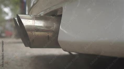 The dual exhaust pipe of a powerful car emitting smoke. Footage. Exhaust fumes and pollution ...