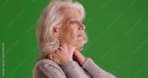 Elderly female with sore neck looking uncomfortable on green screen Stock Photo | Adobe Stock