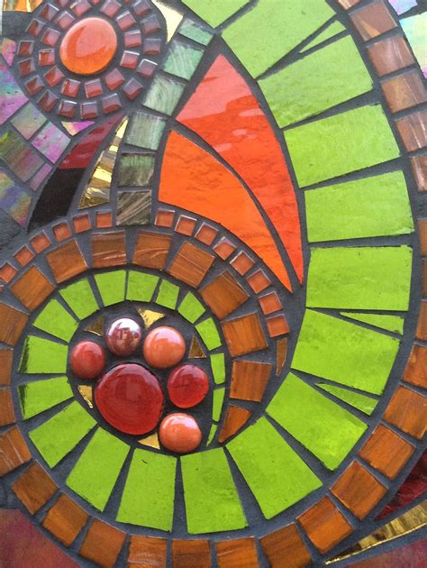 a close up of a stained glass window with red, green and orange designs on it