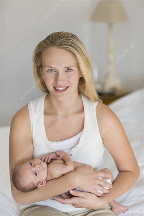 Mother cradling newborn baby on bed - Stock Image - F013/7266 - Science Photo Library