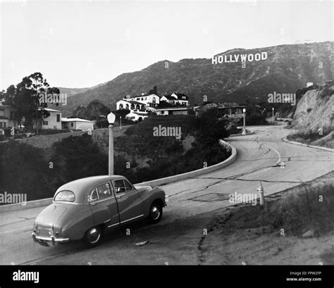 1950s AUSTIN CAR DRIVING UP THE HOLLYWOOD HILLS WITH HOLLYWOOD SIGN IN ...