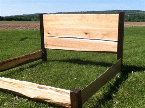a wooden bed frame sitting in the middle of a grass covered field next to a blue sky