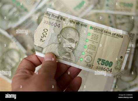 A woman hand holding a torn new Rs 500 Rupees Indian Currency notes showing Mahatma Gandhi ...