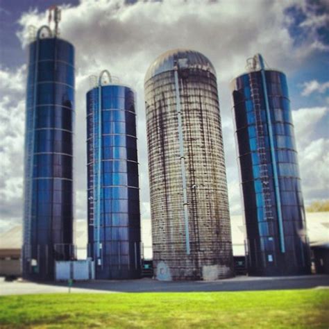 three large blue silos sitting next to each other on top of a green field