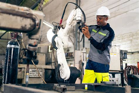 African American factory worker working with adept robotic arm in a ...