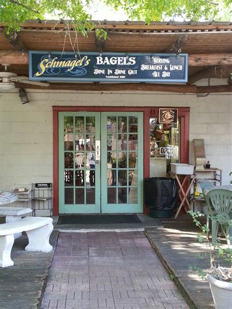 the front entrance of a bagel shop with benches and tables in front of it