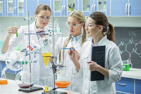 Young female scientists in lab coats making experiment in chemical ...