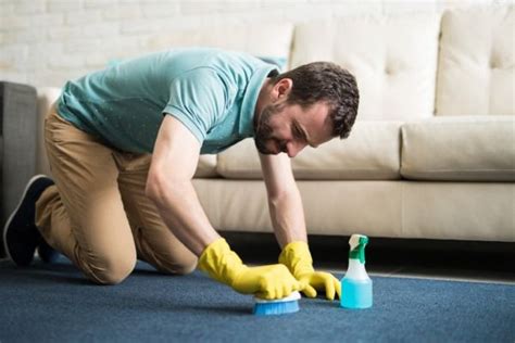 a man is cleaning the floor with a blue bottle and yellow gloves on his ...