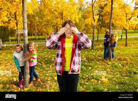 Group of five kids play hide and seek with boy counting and friends ...