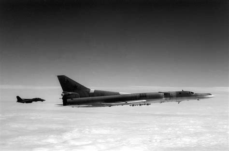 A Soviet Tu-22M Backfire-B bomber aircraft is escorted by an F-14A ...