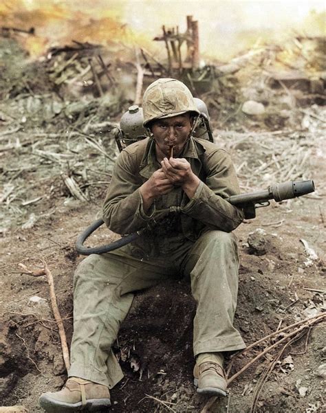 A U.S. Marine with an M2-2 flamethrower strapped to his back stops to ...