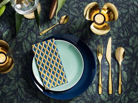 IKEA - Dinner setting with brass-coloured cutlery and candleholder and dark and light blue ...