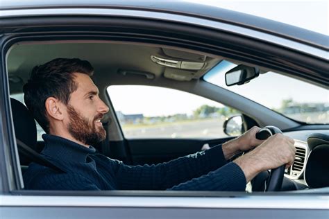 Side view of the handsome businessman driving car before buying. Attractive elegant man in ...