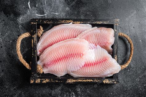 Premium Photo | Fresh tilapia white fish fillet in a wooden tray black ...