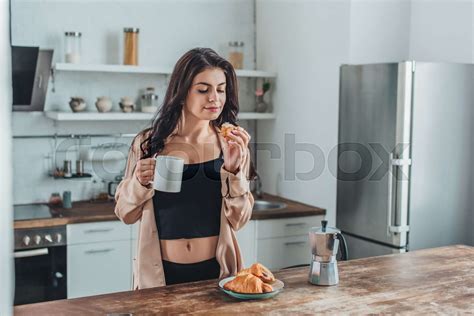 pretty girl having breakfast with croissants and coffee at wooden table ...