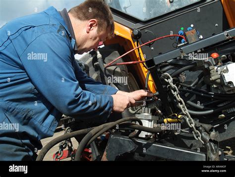 farm worker repairing tractor Stock Photo - Alamy