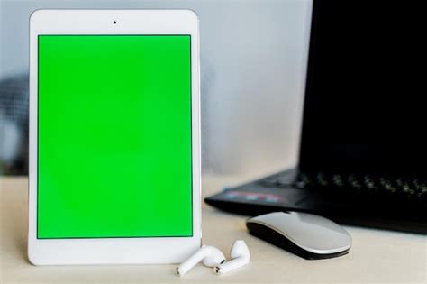 Premium Photo | Tablet with green screen next to a laptop on a desk technology and business concept