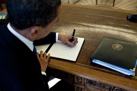 File:Barack Obama signs at his desk.jpg - Wikimedia Commons