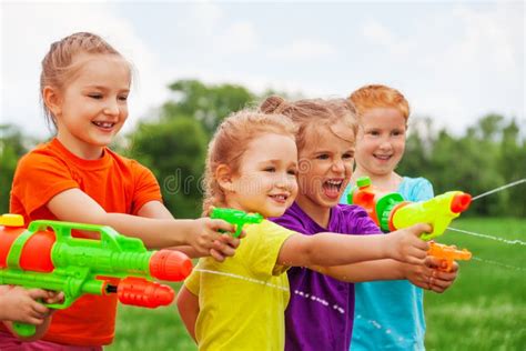 Kids Play With Water Guns On A Meadow Stock Photo - Image of bright ...