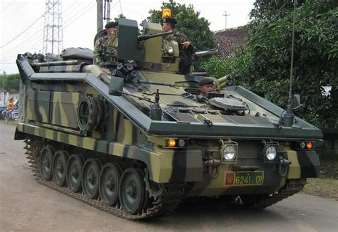 two men are riding on top of an armored vehicle