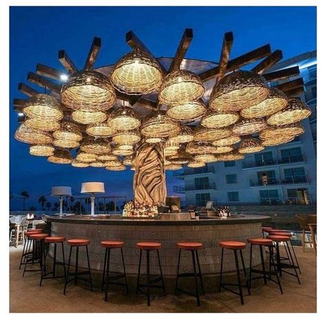 an outdoor bar with many lights hanging from the ceiling and stools at the end