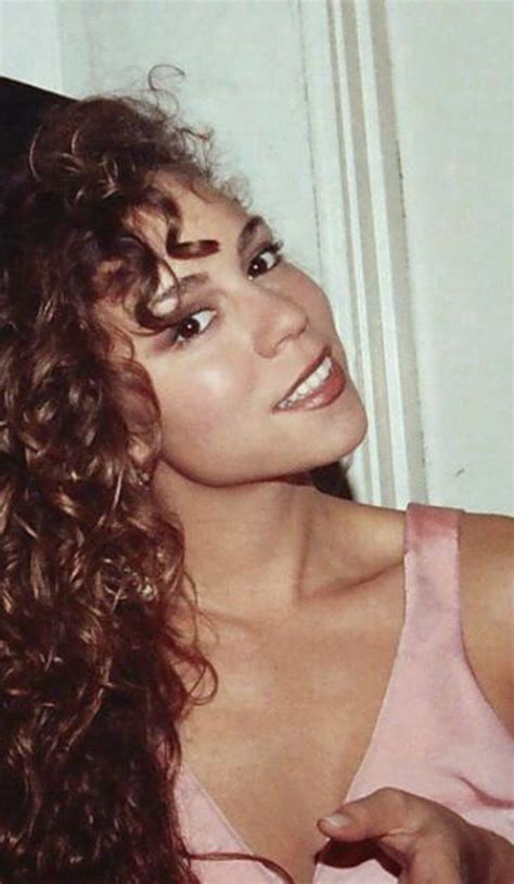 a close up of a person wearing a pink shirt and long curly hair with ...