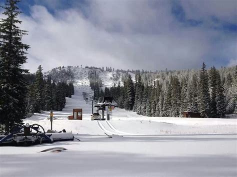 a snow covered ski slope with trees in the background