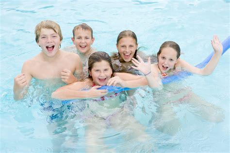 Five young friends in swimming pool playing and smiling - Lice Clinics of Texas