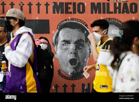 FILE - Demonstrators walk past a mural depicting the face of Brazilian ...