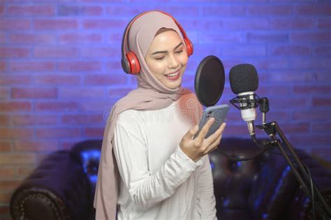 Young Smiling Muslim Female Singer Wearing Headphones with a Microphone ...