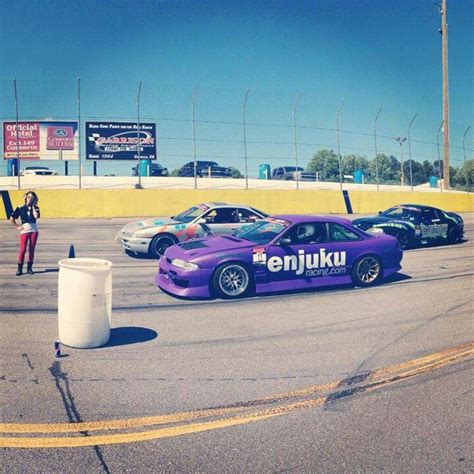 some cars are racing on a track with one person standing next to the race car