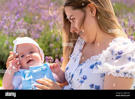 Young mother watching her happy gurgling baby boy cradled in her arms ...