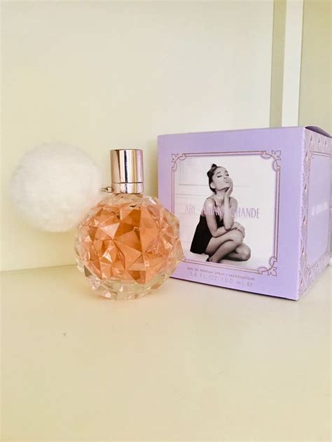 a bottle of perfume next to a box with a pom - pom on it