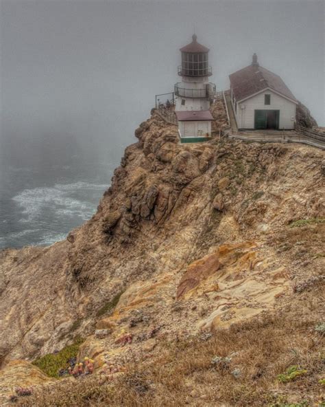 a lighthouse sitting on top of a cliff next to the ocean