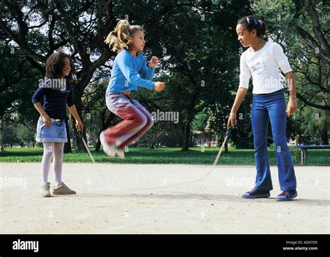 Children kids girls children jumping rope three standing holding mid air park fun physical ...