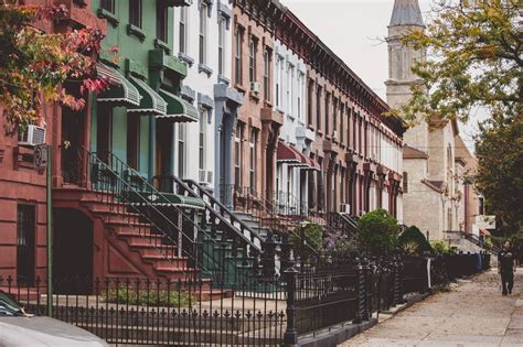 a row of browns houses on a city street with a steeple in the background