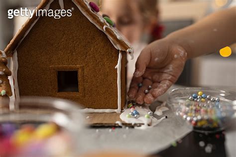 Close up of little girl adding colorful sprinkles on a gingerbread ...