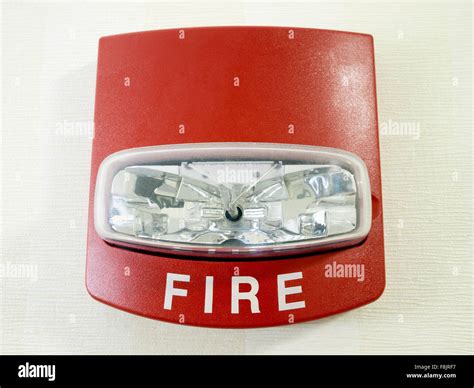 Red fire alarm strobe light smoke detector mounted on a wall as part of a commercial fire ...