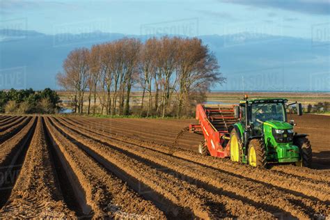 Rural landscape, tractors ploughing and sowing fields in early Spring time at Burnham Overy ...